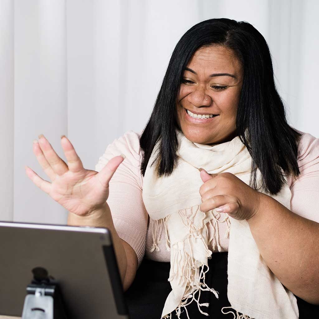 A Polynesian woman is signing while communicating through video chat from her tablet.